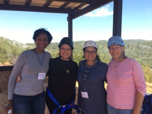 Group of four women in helmets waiting for their turn on the zipline